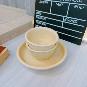 Detailed close-up view of the cream ceramic tableware set with cute bowls and a plate.