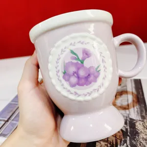 Close-up of vintage ceramic mug detail featuring purple floral pattern and elegant lace relief.