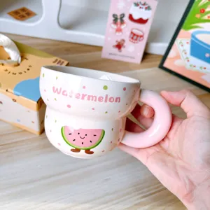 Detalle de taza de café de cerámica con asa gruesa, forma de calabaza y diseño de sandía.