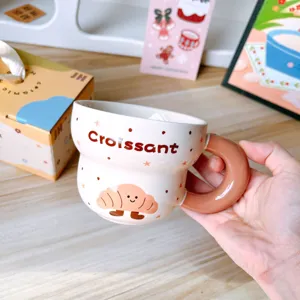 Primer plano de la bonita taza de café de cerámica croissant con asa gruesa para el desayuno.