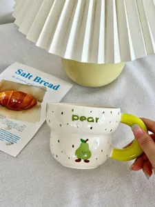 Cute ceramic coffee mug with pear pattern and green handle, perfect for daily use.