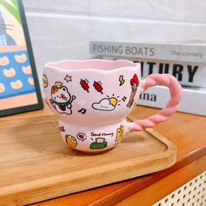Leuke roze keramische koffiemok met speels gedraaid handvat en schattige kattenmotieven op kantoor.