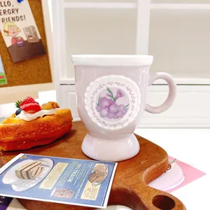 Light purple ceramic coffee mug featuring floral medallion and elegant footed base.