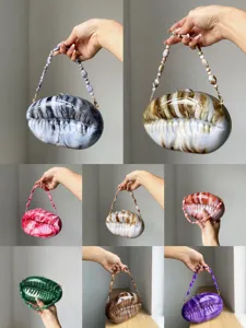 Closeup details of unique seashell acrylic evening clutch bag with beaded chain handles.
