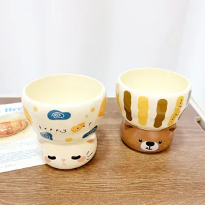 Detail shot of creative ceramic water cup featuring cute animal base and printed text design.