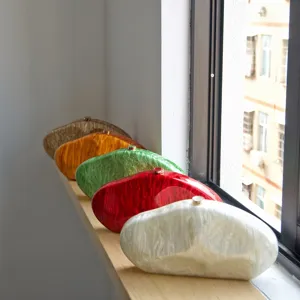 Detailed view of colorful irregular acrylic clutch bags arranged neatly on wooden window sill.