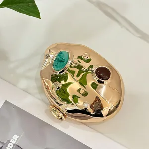 Closeup of creative irregular metallic gold evening clutch bag with colorful decorative stone details.