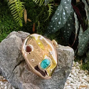 Metallic gold irregular clutch bag detail, luxury evening bag with colorful gemstone accents.