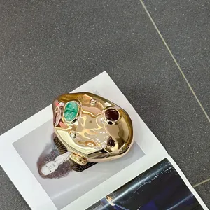 Metallic irregular evening bag with green and red stone decoration for chic parties.