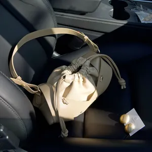 Chic beige leather bucket bag with drawstring closure, pleated design and stylish cross straps.