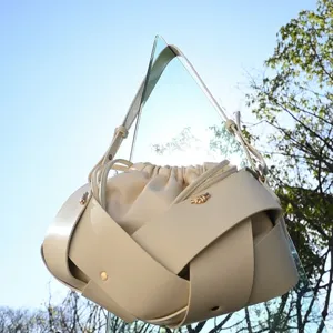 Retro beige soft leather bucket bag featuring unique crossed strap design and drawstring.