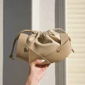 Beige leather drawstring crossbody bag, soft pleated bucket bag with chic cross straps and gold.