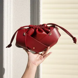 Retro leather drawstring crossbody bag with cross straps, soft pleated niche luxury bucket bag detail.