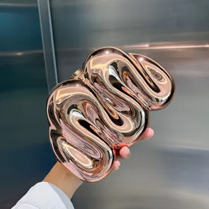 Nahaufnahme des kreativen glänzenden metallischen unregelmäßigen Clutch-Täschchens mit Design.