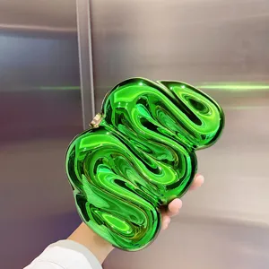 Detailaufnahme der kreativen Acryl-Clutch mit glänzendem metallic grünem Wirbel-Design.