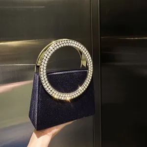 Nahaufnahme der dunklen, glitzernden Abendtasche mit glamourösem Strass-Rundgriff.