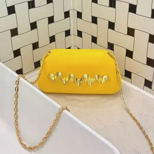 Close-up view of the yellow frosted box bag featuring a metallic wave decor and chain.