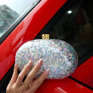 Glitter acrylic clutch bag close-up detail showing sparkling texture and gold clasp.