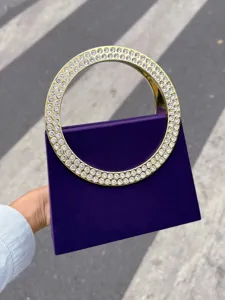 Detailansicht der lila Abendtasche mit glamourösem goldenen Strass-Kreisgriff.