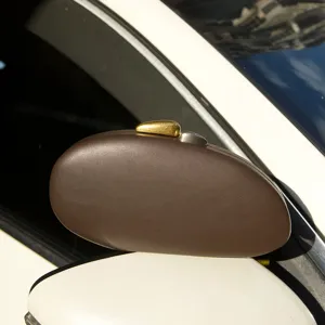 Brown matte acrylic evening clutch bag detail view, unique pebble shell shape, metal clasp.