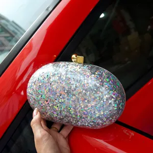 Acrylic holographic glitter oval clutch bag detail showing sparkling sequin texture and gold clasp.