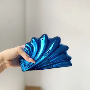 Detailansicht der glänzenden blauen Acryl-Muschel-Clutch mit einzigartiger Textur und Metallglanz.