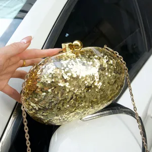Gold glitter acrylic oval clutch bag detail showing sparkling sequins and metal chain strap.