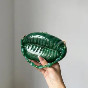 Close-up detail of dark green gradient acrylic shell evening bag with beaded handle texture.