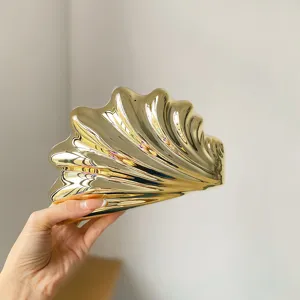Detailansicht der goldenen Muschel-Clutch, glänzende Acryl Abendtasche im Nahbereich.