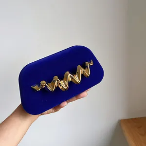 Elegant blue velvet box clutch bag featuring a luxurious metallic gold wavy design detail.
