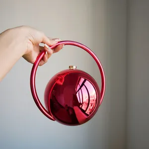 Detailaufnahme der roten runden Metallabendtasche, glänzende galvanisierte Oberfläche Griff.