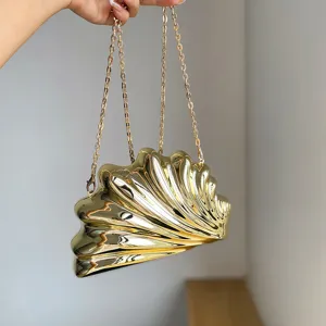 Detailaufnahme der luxurioesen goldenen Acryl-Muscheltasche mit glaenzender Metallkette.