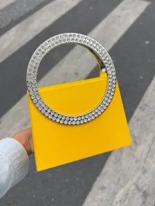 Detailansicht der luxuriösen gelben Abendtasche mit funkelndem Strass-Kreisgriff.