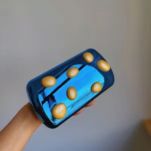 Detailaufnahme der glänzenden blauen Metall Abendtasche mit gelben 3D Kieselsteinen.