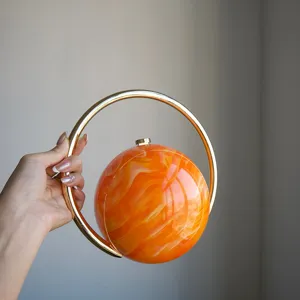 Elegante kugelformige Abendtasche mit orangenem Marmormuster und luxuriosem Goldringgriff.