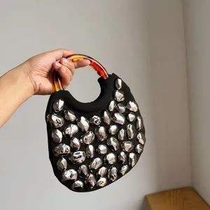 Chic black fabric handbag with metallic silver pebble studs and stylish tortoiseshell ring handle.