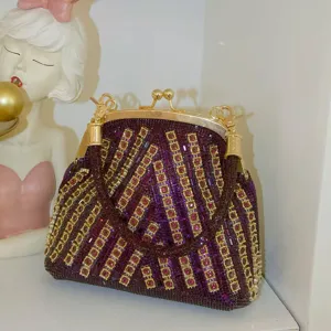 Sparkly purple rhinestone evening clutch bag with gold frame, elegant and compact design for party.