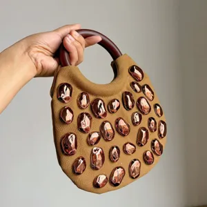Detail view of stylish canvas handbag featuring wooden handle and metallic rivet decorations for women.