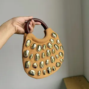Close-up of the stylish fabric handbag with metallic stone studs and round wooden handle.