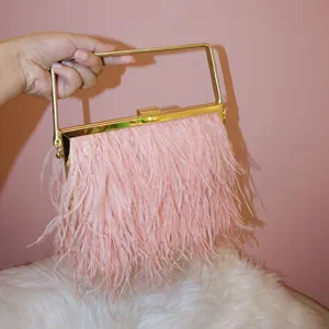 Detail view of an elegant pink feather evening bag featuring a sleek gold metal top handle.