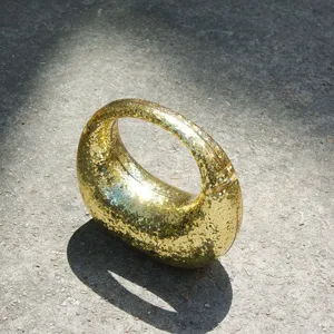 Close-up of the gold glitter crescent handbag featuring a sleek curved handle and shimmer finish.