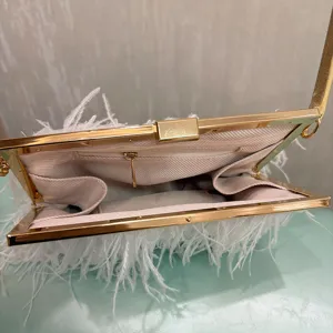 Detail view of the stylish white feather evening bag showing metal clasp and interior lining structure.
