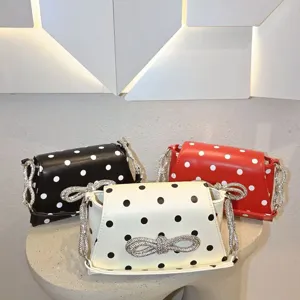 Detailansicht der stilvollen Pünktchen-Umhängetasche mit funkelnder Strass-Schleife.