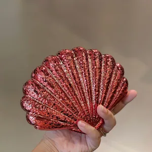 Detail view of the red metallic acrylic shell evening clutch bag showing shiny texture and unique design.