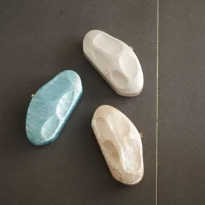 Detailed view of irregular acrylic evening clutches in blue, white, and beige with stone texture.