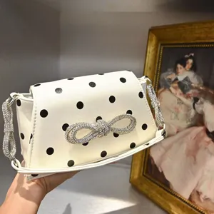 Nahaufnahme Detail der weißen Punkte Umhängetasche mit funkelnder Strass Schleife und Riemen.