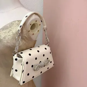 Weißer Pünktchen-Umhängetasche mit funkelnder Strass-Schleife und glamourösen Kettengriffen.