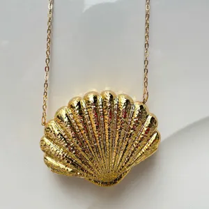 Golden shell evening bag detail, metallic chain strap and textured surface close up view.