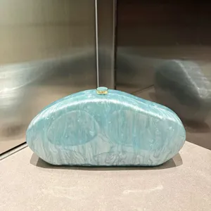 Detailed view of light blue marbled acrylic clutch bag, elegant irregular evening purse.