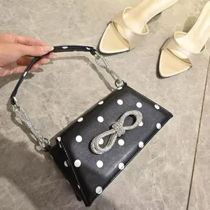 Schwarz-weiße Punkt-Umhängetasche mit Strass-Schleife und funkelndem Kettengriff für Damen.